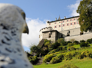 Hohenwerfen Fortress - The castle Hohenwerfen Fortress - view past a falcon statue to the linden meadow and the castle