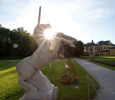 Ausflugstipps Schloss Hellbrunn & Wasserspiele - Einhorn-Statue von Sonnenstrahlen hinterleuchtet im Park